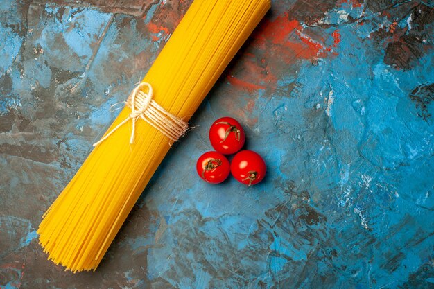 Vue rapprochée des pâtes vermicelles attachées avec de la corde et des tomates sur fond bleu