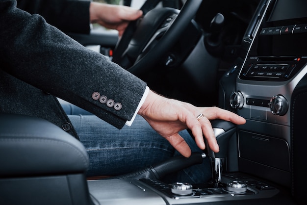 Vue rapprochée de la personne adulte change de vitesse dans la nouvelle voiture de luxe