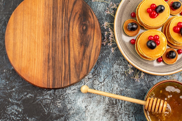 Vue rapprochée de la planche à découper en bois rond crêpes aux fruits et miel sucré