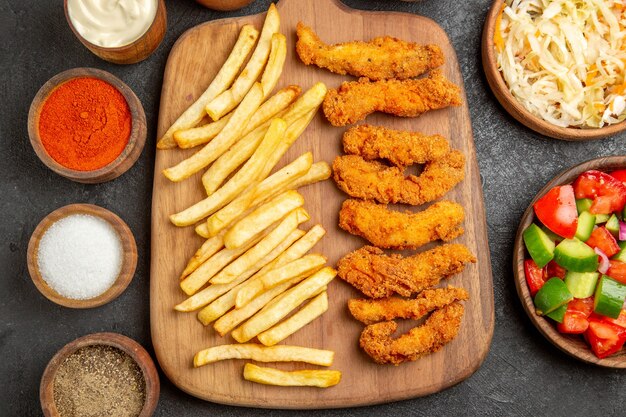 Vue rapprochée de pommes de terre au poulet frit différentes épices et choucroute avec salade sur table sombre