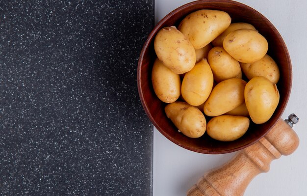 Vue rapprochée de pommes de terre dans un bol avec du sel et une planche à découper sur tableau blanc