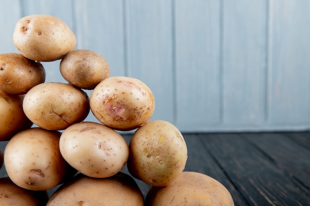 Photo gratuite vue rapprochée de pommes de terre en forme de pyramide sur le côté gauche et fond en bois avec copie espace