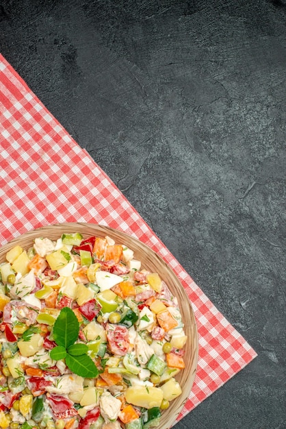 Vue rapprochée de la salade de légumes dans un bol sur une serviette rouge sur fond gris foncé