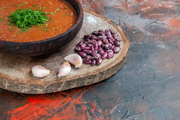 Vue rapprochée de la soupe aux tomates haricots ail sur une planche à découper en bois sur la table des couleurs de mélange