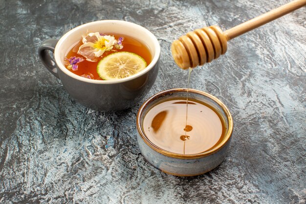 Vue rapprochée d'une tasse de thé au citron et miel sur fond gris
