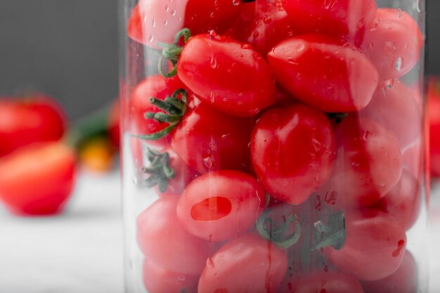 Vue rapprochée de tomates cerises humides mûres fraîches dans un bocal en verre