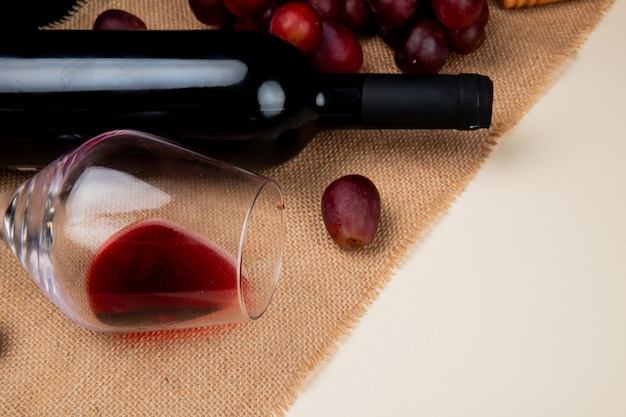 Vue rapprochée de vin rouge et raisin sur un sac sur fond blanc