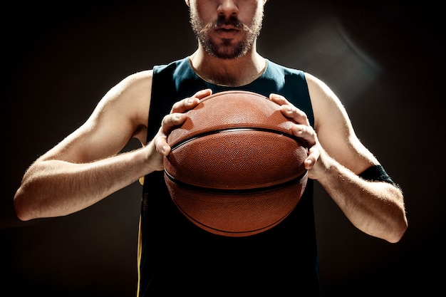 Photo gratuite vue silhouette, de, a, basketteur, tenue, basket-ball, sur, mur noir