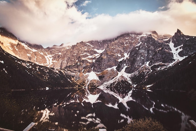 Vue spectaculaire sur les belles montagnes avec réflexion en miroir et nuages au lever du soleil.