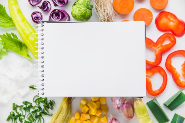 Vue surélevée du bloc-notes en spirale blanc sur des légumes sains frais