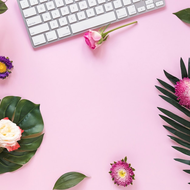 Vue surélevée de fleurs et clavier sur fond rose