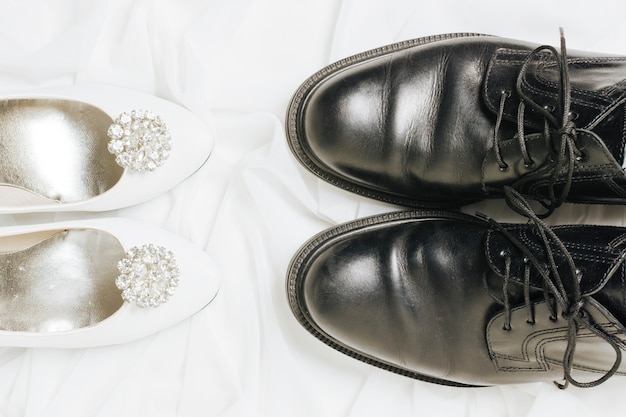 Une vue surélevée de hauts talons blancs et de chaussures noires sur le foulard