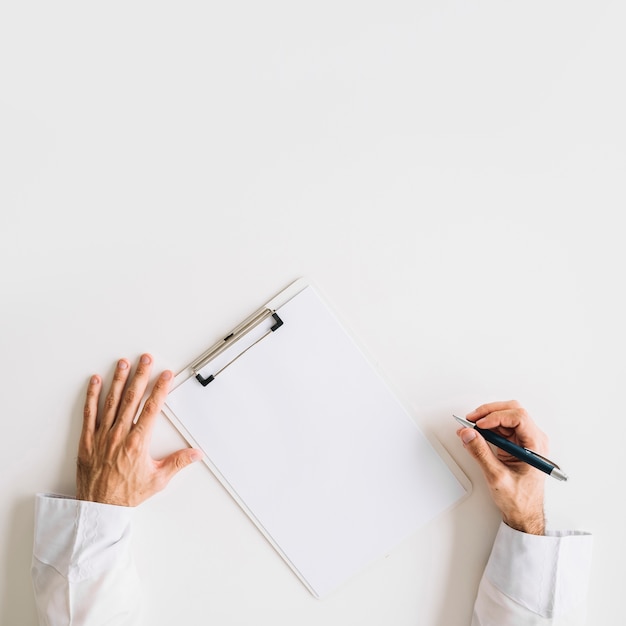 Vue surélevée de la main du docteur avec du papier blanc vierge