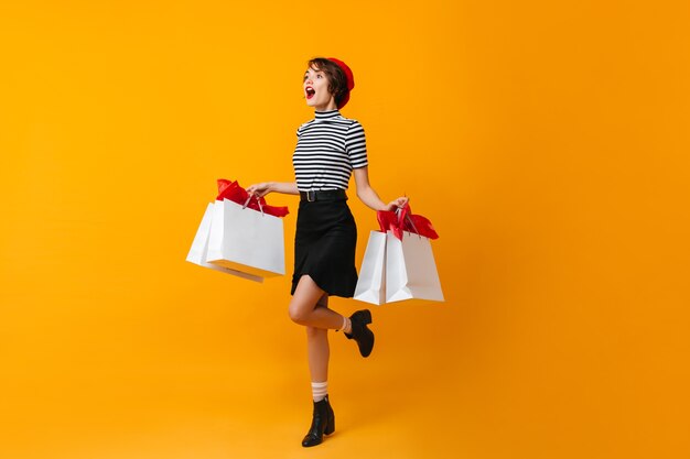 Vue sur toute la longueur de la femme mince excitée avec des sacs de magasin