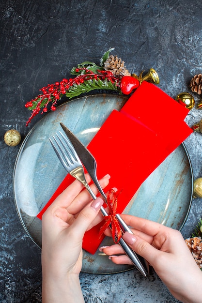 Vue verticale de l'ambiance de Noël avec la mise en place d'une table avec un ensemble de couverts et une assiette bleue sur fond sombre