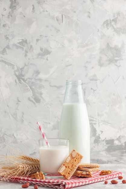 Photo gratuite vue verticale de bonbons en forme de bâton dans une bouteille en verre remplie de lait et de pâtisseries cacahuètes sur une serviette dépouillée rouge sur fond gris