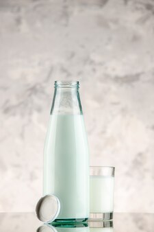 Vue verticale d'une bouteille en verre et d'une tasse remplie de bouchon de lait sur fond de fumée blanche avec espace libre