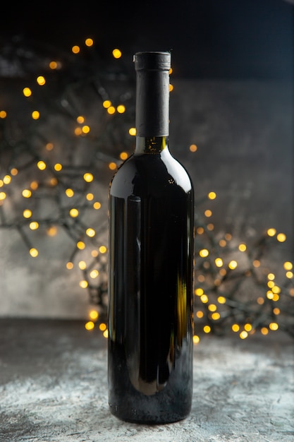 Vue verticale de la bouteille de vin en verre rouge pour la célébration sur une table sombre