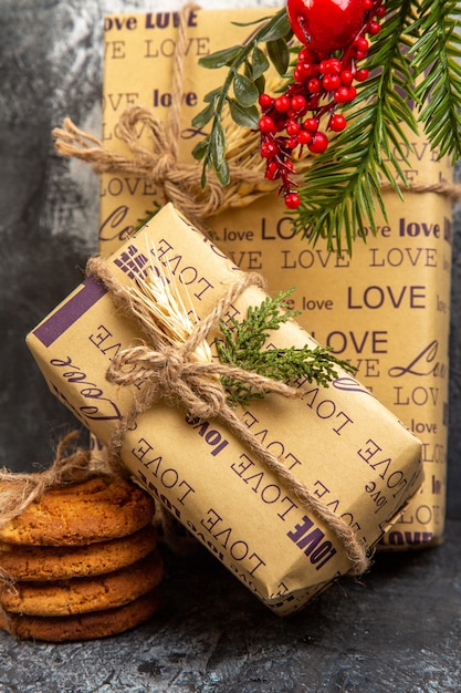 Vue verticale des cadeaux emballés pour les membres de la famille debout sur le mur et des biscuits empilés sur fond sombre