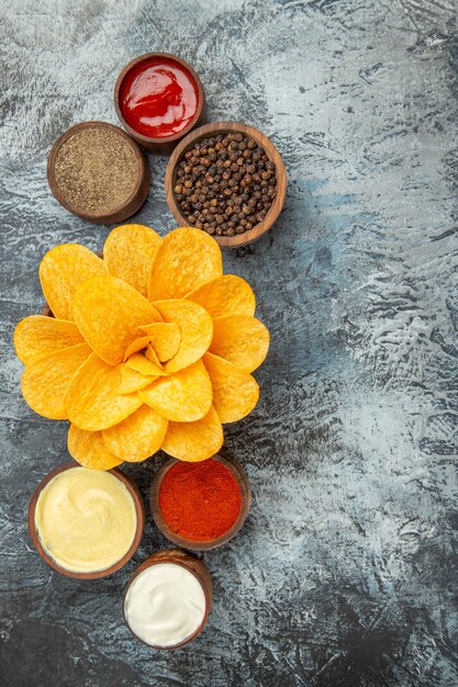 Vue verticale de chips maison décorées comme une fleur en forme dans un bol brun sur fond gris