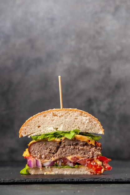 Vue verticale de couper des sandwichs savoureux sur un plateau noir sur une surface de couleur mélange sombre