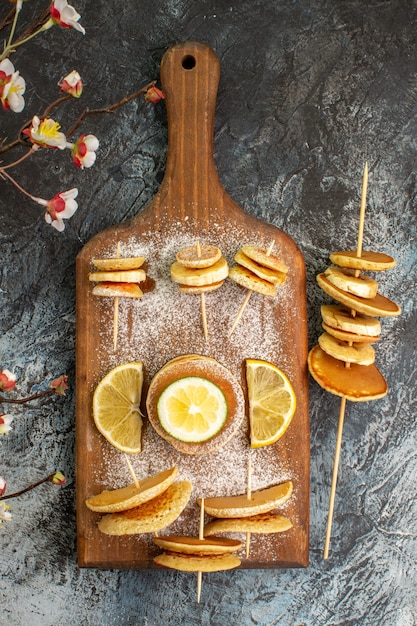 Vue verticale de crêpes américaines classiques aux citrons sur une planche à découper en bois sur fond gris