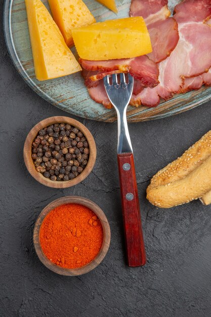 Vue verticale d'une délicieuse tranche de saucisse et de fromage sur une assiette bleue poivrons sur fond sombre