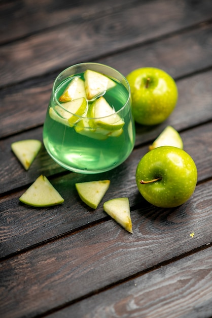 Photo gratuite vue verticale de délicieux jus dans un verre et une pomme sur fond sombre