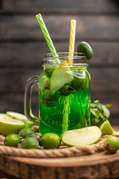 Vue verticale de délicieux jus de fruits frais servis avec pomme et feijoas sur une planche à découper en bois sur une table marron