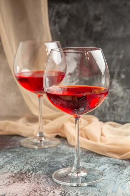 Vue verticale de deux verres de délicieux vin rouge sec et serviette sur fond de glace