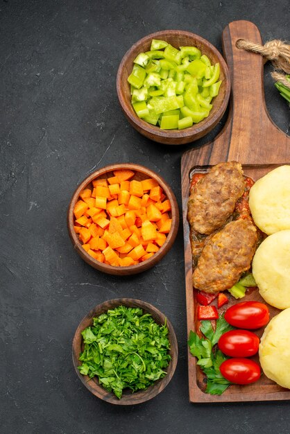 Vue verticale du dîner. avec de savoureuses côtelettes de légumes et verts sur fond noir