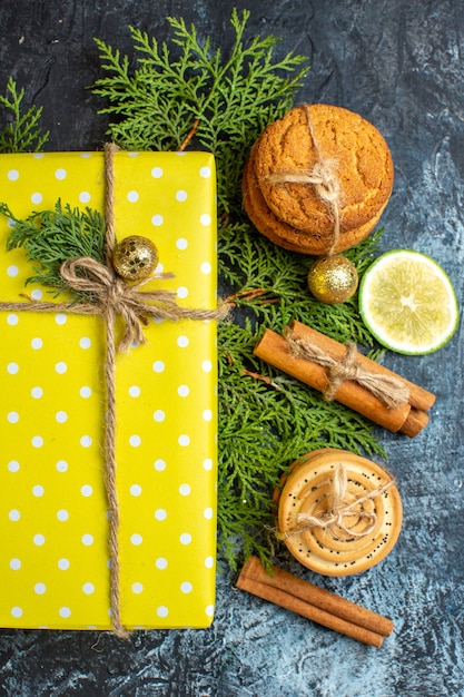 Vue verticale du fond de Noël avec de belles boîtes-cadeaux jaunes et des biscuits empilés au citron sur une table sombre