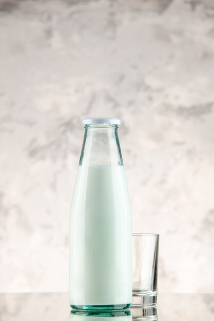 Vue verticale fermée et remplie d'une bouteille en verre de lait et d'une tasse sur un mur de fumée blanche avec espace libre