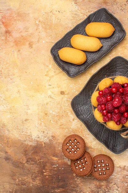 Vue verticale d'un gâteau cadeau et biscuits sur des assiettes brunes sur fond de couleur mixte