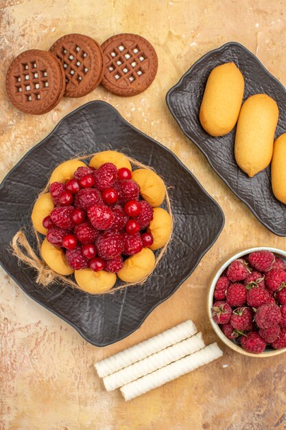 Vue verticale d'un gâteau cadeau et biscuits sur assiettes brunes fruits sur fond de couleur mixte