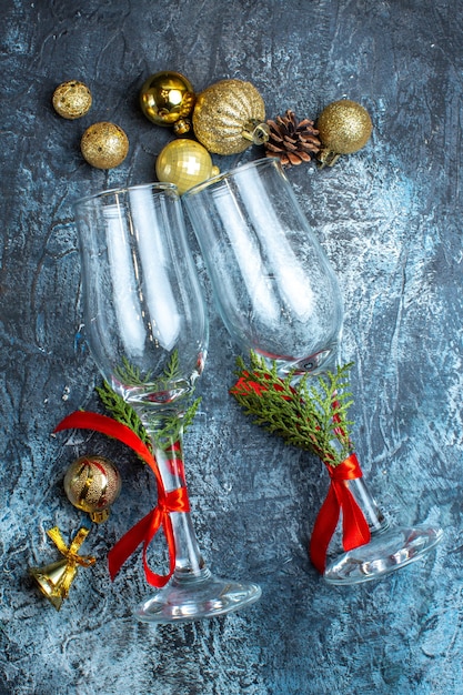 Vue verticale des gobelets en verre avec ruban rouge et accessoires de décoration sur fond sombre