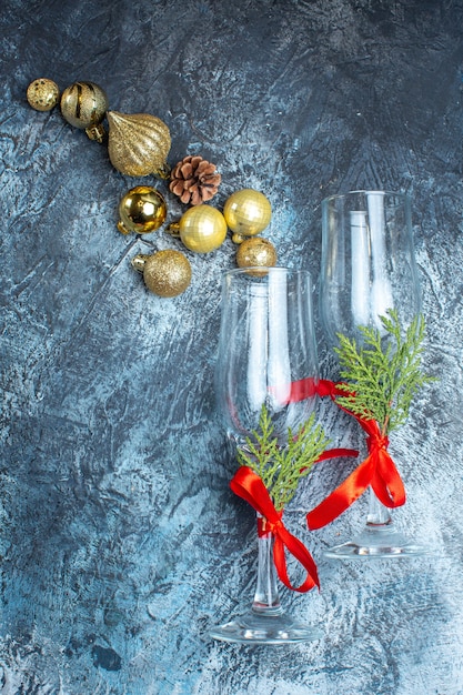 Vue verticale des gobelets en verre avec ruban rouge et accessoires de décoration sur fond sombre