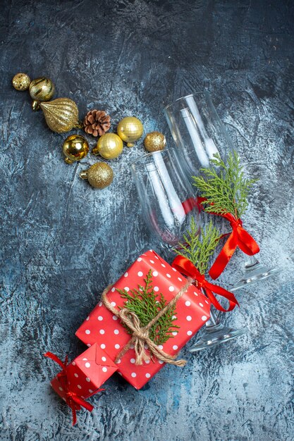 Vue verticale des gobelets en verre tombés et des coffrets cadeaux rouges et accessoires de décoration sur fond sombre