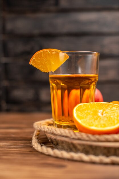 Vue verticale de jus frais bio en bouteille servi avec tubes et fruits sur le côté gauche sur une table en bois marron