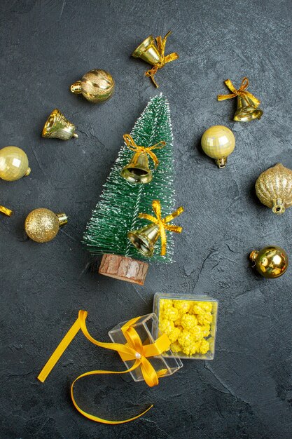 Vue verticale de la main tenant les coffrets cadeaux accessoires de décoration et arbre de Noël sur fond sombre