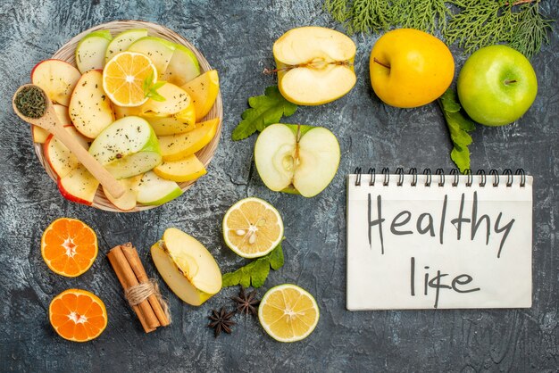 Vue verticale d'un ordinateur portable avec une vie saine et une collection de tranches de pommes biologiques naturelles fraîches sur une plaque blanche sur fond sombre