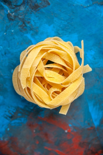 Photo gratuite vue verticale des pâtes fraîches faites maison de tagliatelles sur le fond bleu