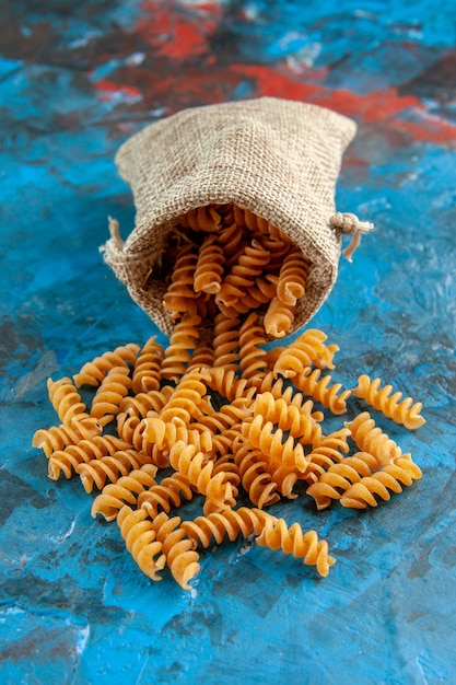 Vue verticale des pâtes italiennes crues du sac à main gris sur fond bleu
