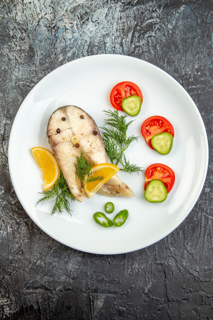 Photo gratuit vue verticale des poissons crus et des aliments frais au poivre sur une plaque blanche sur une surface de glace grise