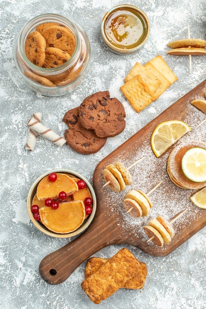 Vue verticale de simples crêpes aux citrons sur une planche à découper et biscuits miel sur bleu