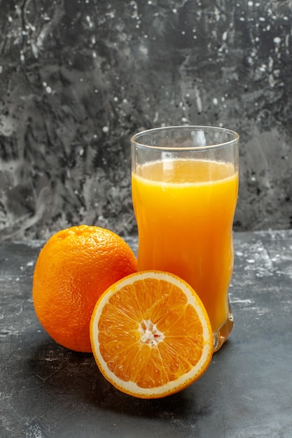 Photo gratuite vue verticale de la source de vitamines coupée et des oranges et jus frais entiers sur fond gris