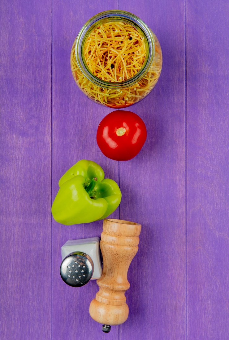 Photo gratuit vue verticale de spaghetti macaroni au sel de poivron tomate sur table violette