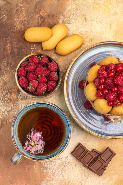 Vue verticale d'une tasse de tisane chaude soft cake avec des barres de chocolat aux fruits sur table de couleurs mixtes