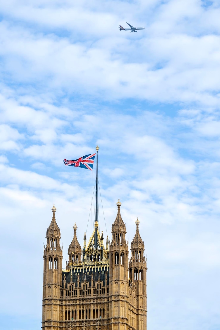Photo gratuit vue verticale de la tour victoria située dans le palais de westminster au centre-ville de londres royaume-uni ciel bleu avec avion volant en arrière-plan