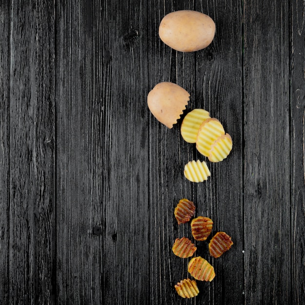 Vue verticale des tranches de croustilles de pommes de terre entières et coupées sur le côté droit et fond en bois avec copie espace